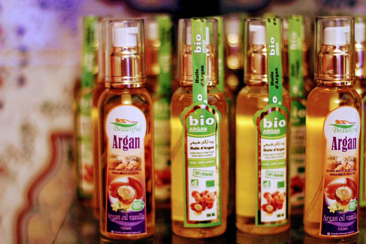 Amber glass dropper bottles of facial and hair oils arranged on a wooden surface, representing the range of oils used for moisturizing hair.