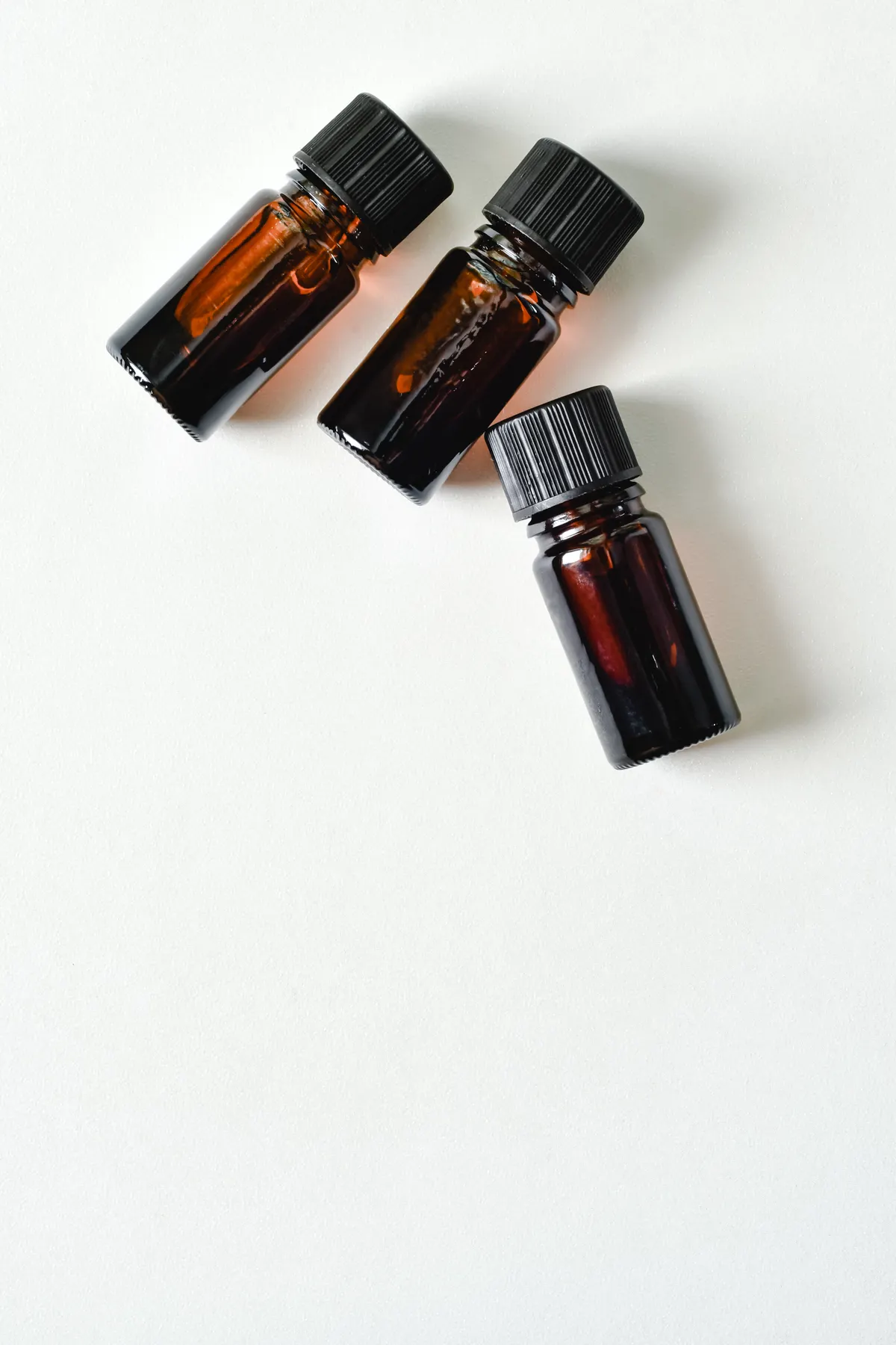 Amber glass aromatherapy bottles, similar to those used for REVIVE Essential Oils products, arranged on a plain surface.