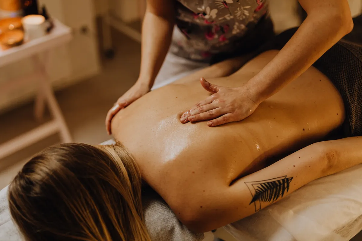 A woman receiving a relaxing back massage in a spa setting, the kind of full-body session where a light, unscented oil matters most.