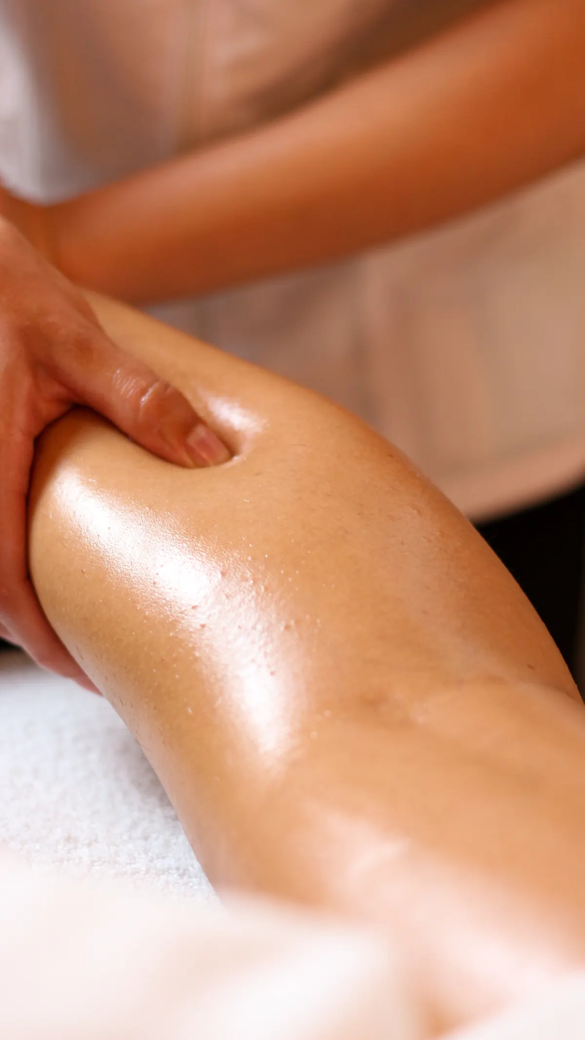 Close-up of a relaxing leg massage in a spa setting, the same long, sweeping strokes worth using for a DIY foot massage oil treatment at home.