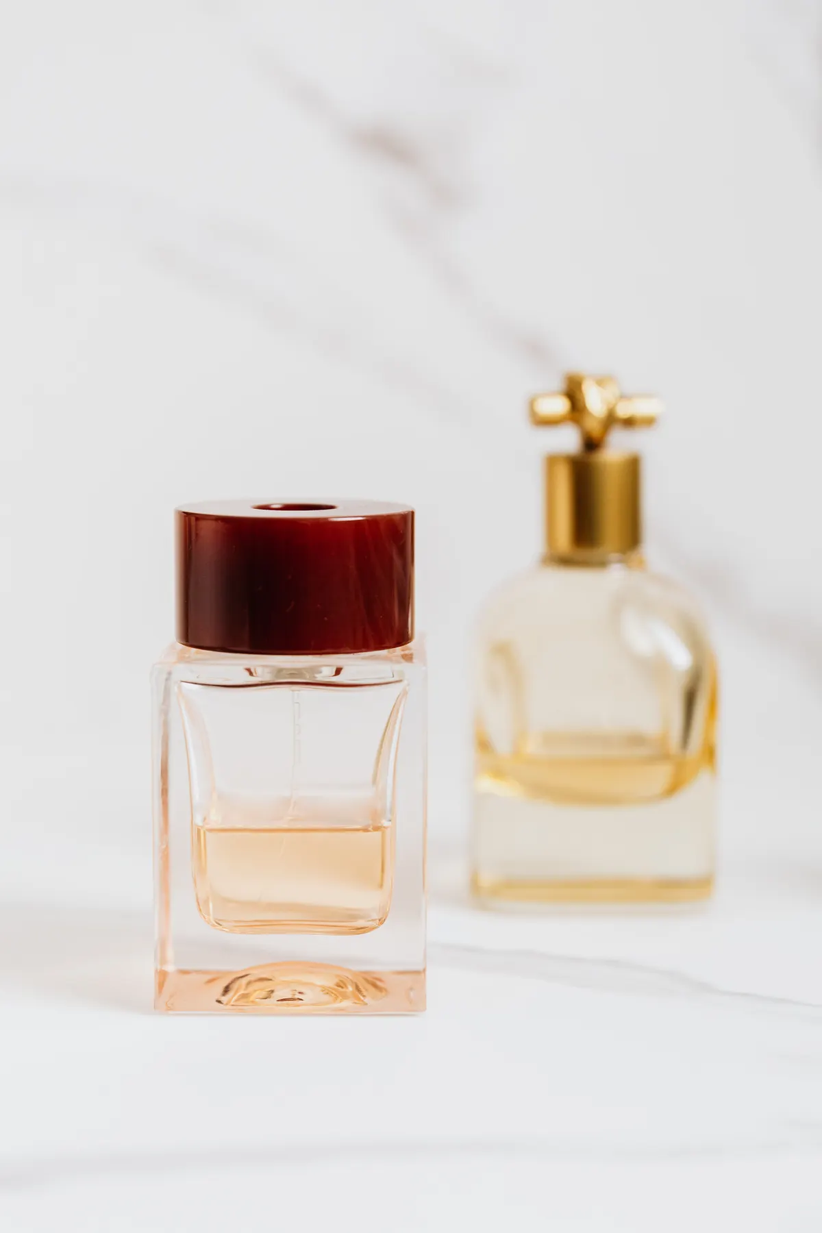 Elegant glass bottles of natural perfume essential oils arranged on a marble surface.