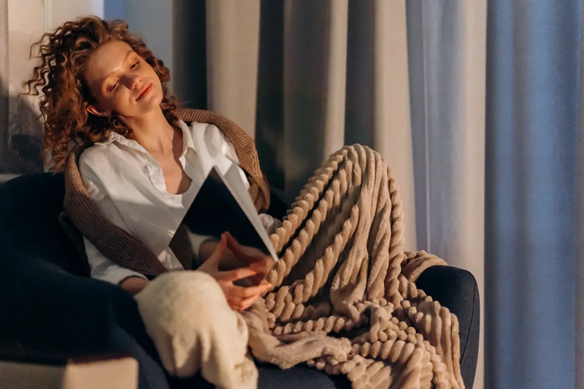 A woman relaxing at home in the evening, the kind of unhurried moment worth pairing with a foot massage.